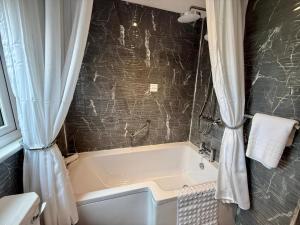 a bathroom with a bath tub with a shower curtain at Carron Cottage in Inverness