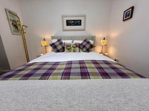 a bedroom with a large bed with two lamps at Carron Cottage in Inverness