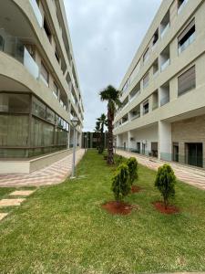 a building with two palm trees in front of it at Two bedroom Apartment in Bouznika Beach in Bouznika