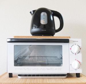 a tea kettle sitting on top of a microwave at Harbor Nook Takamatsu in Takamatsu