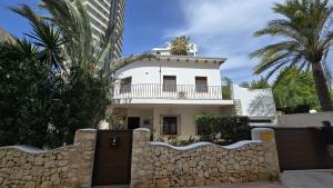 a house with a fence and palm trees at Villa Los Gemelos in Calpe