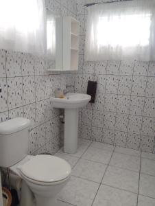 a white bathroom with a toilet and a sink at Roche Kerlan Apartments in Anse Kerlan