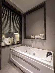 a white bath tub in a bathroom with a mirror at The LC Hotel in Lahore