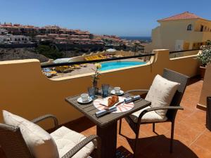 a table with food on a balcony with a pool at Sunny Apartment Loma de Arguineguín in Arguineguín