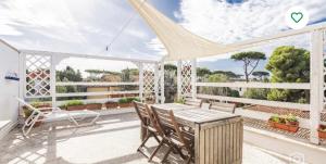 a white porch with a wooden table and chairs at Casa di Clara Fregene in Fregene