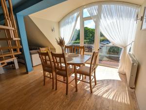 a dining room with a table and chairs and a large window at Atostogos Pervalkoje in Pervalka