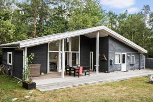 a black house with a deck and a table at 4317-Stege-Oddermosevej-6 in Stege