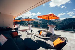 a patio with chairs and umbrellas with a view of mountains at Hotel Prätschli in Arosa +40 photos