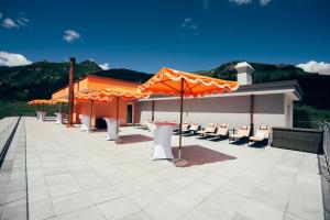 a patio with white chairs and orange umbrellas at Hotel Prätschli in Arosa