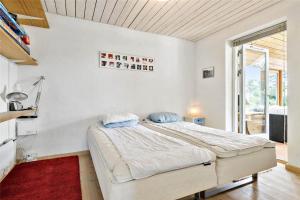 a white bedroom with a bed and a window at R744-Rodvig-Poppelager-7 in Rødvig