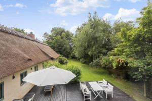 a patio with an umbrella and chairs on a deck at R970-Rodvig-Havnelev-Enghave-1 in Rødvig