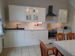 a kitchen with white cabinets and a sink and a table at Ferienwohnung Bottrop Radetzki in Bottrop