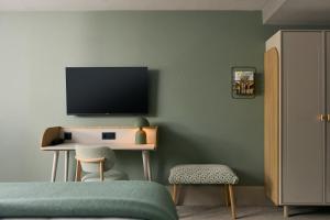 1 dormitorio con TV y escritorio con silla en Van der Valk Hotel Volendam - Recently renovated, en Volendam