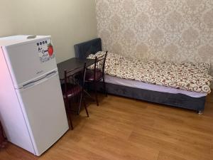 a room with a refrigerator and a table with a bed at Hotel Yuzhanka in Sanzhiyka