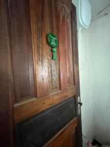 una puerta de madera con una señal verde. en Camping do Ser - Quarto Montanha, en Petrópolis