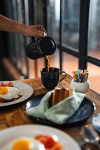 a person pouring coffee into a cup on a table at The Casa Amaya in Jimbaran