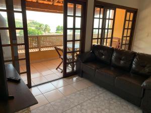 a living room with a leather couch and a balcony at Blue View Escape in São Sebastião