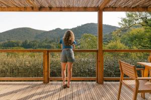 a woman standing on a deck looking out at the mountains at Slow Village Anduze - Cévennes in Corbés