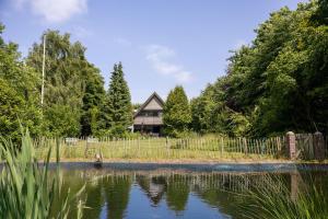 Una casa situada junto a un estanque con una valla. en Stilbjerg Sleep&Hygge, en Varde