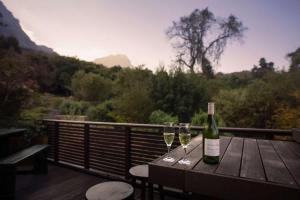 a bottle of wine sitting on a table with two glasses at Table Mountain Villa in Cape Town