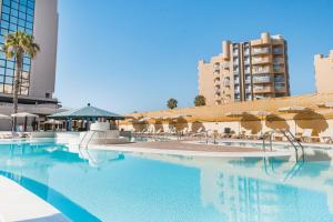 a swimming pool with chairs and umbrellas and buildings at Bakour La Manga Splash in La Manga del Mar Menor