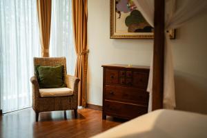 a bedroom with a chair and a dresser with a green pillow at The Casa Amaya in Jimbaran +35 photos