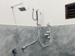 a shower in a bathroom with a phone on the wall at 2nd Home Villa in Pottuvil