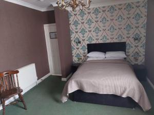 a bedroom with a bed with a chandelier and a chair at Edenfield Lodge in Blackpool