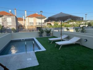 a backyard with a swimming pool and chairs and an umbrella at Trinity Pool Villas WHITE in Iraklitsa
