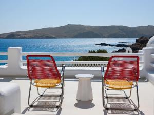 2 stoelen en een tafel op een balkon met uitzicht op het water bij Mykonos Lolita, A Grecotel Resort to Live in Agios Sostis Mykonos