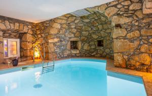 a large swimming pool with a stone wall at Stone House Zijavica with indoor pool in Mošćenička Draga