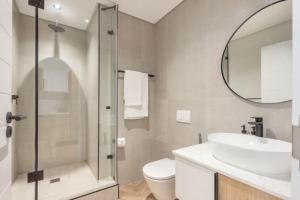 a bathroom with a sink and a toilet and a mirror at On Park - Century City Lux Studio Apartment in Cape Town +19 photos
