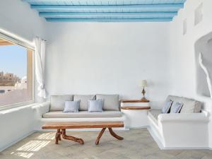 een woonkamer met een bank en een raam bij Mykonos Lolita, A Grecotel Resort to Live in Agios Sostis Mykonos