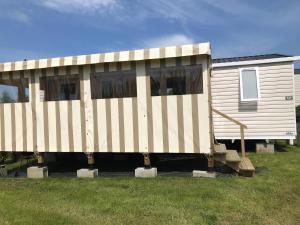 a house that is sitting in the grass at Le Domaine de Litteau 4 étoiles à LITTEAU emplacement 443 3CH 1SDB 6 personnes in Litteau