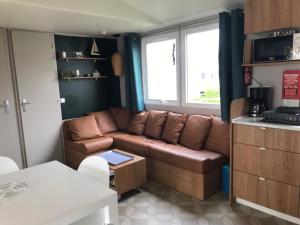 a living room with a brown couch in a kitchen at Le Domaine de Litteau 4 étoiles à LITTEAU emplacement 443 3CH 1SDB 6 personnes in Litteau