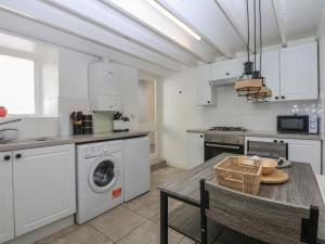 a kitchen with a table and a washing machine at 3 York Place in Conwy +14 photos