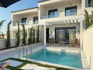 a villa with a swimming pool in front of a house at Bela Villas in Kallithea Halkidikis