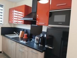 a kitchen with red cabinets and a black refrigerator at A 2 pas des iles à Concarneau in Concarneau