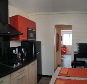 a kitchen with red cabinets and a black refrigerator at A 2 pas des iles à Concarneau in Concarneau