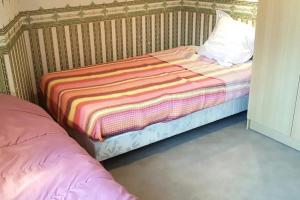 a small bed with a striped blanket and a pillow at Maisons agréables 13ms024 in La Fresnais