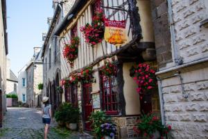 a woman walking down a street with flowers on a building at Maisons agréables 13ms023 in La Fresnais +10 photos