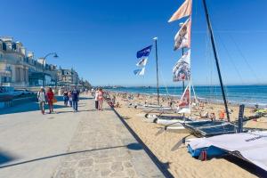 a beach with a lot of people and flags at Maisons agréables 13ms023 in La Fresnais