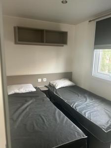 Dos camas individuales en una habitación con ventana. en MOBIL HOME l'ETOURNEAU, en Valras-Plage 7 fotos más