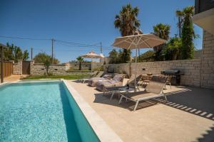 una piscina con tumbonas y sombrillas junto a en Villa Zen Hephaistos by PosarelliVillas, en Asprouliánoi