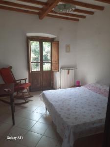 a bedroom with a bed and a chair and a window at casa delle arti in Salutio