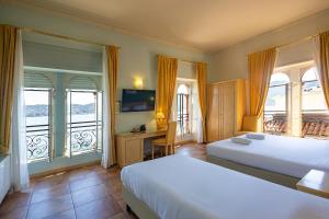 a bedroom with two beds and a desk and windows at LVG Hotel Collection - Belvedere San Gottardo in Verbania