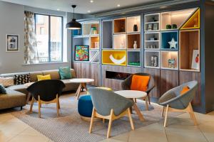 a living room with chairs and a couch and tables at Holiday Inn Belfast by IHG in Belfast +42 photos