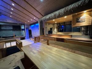 un comedor con mesas de madera y un bar en Yukiguni Base Hakuba, en Hakuba 25 fotos más