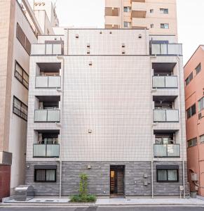 een groot wit bakstenen gebouw met balkons bij Sheath Okachimachi Apartment Hotel in Tokyo