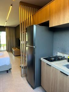 a kitchen with a stainless steel refrigerator next to a bed at Vilas Manatee - Praia do Patacho in Pôrto de Pedras